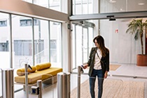 A woman scanning an access badge to enter an office space