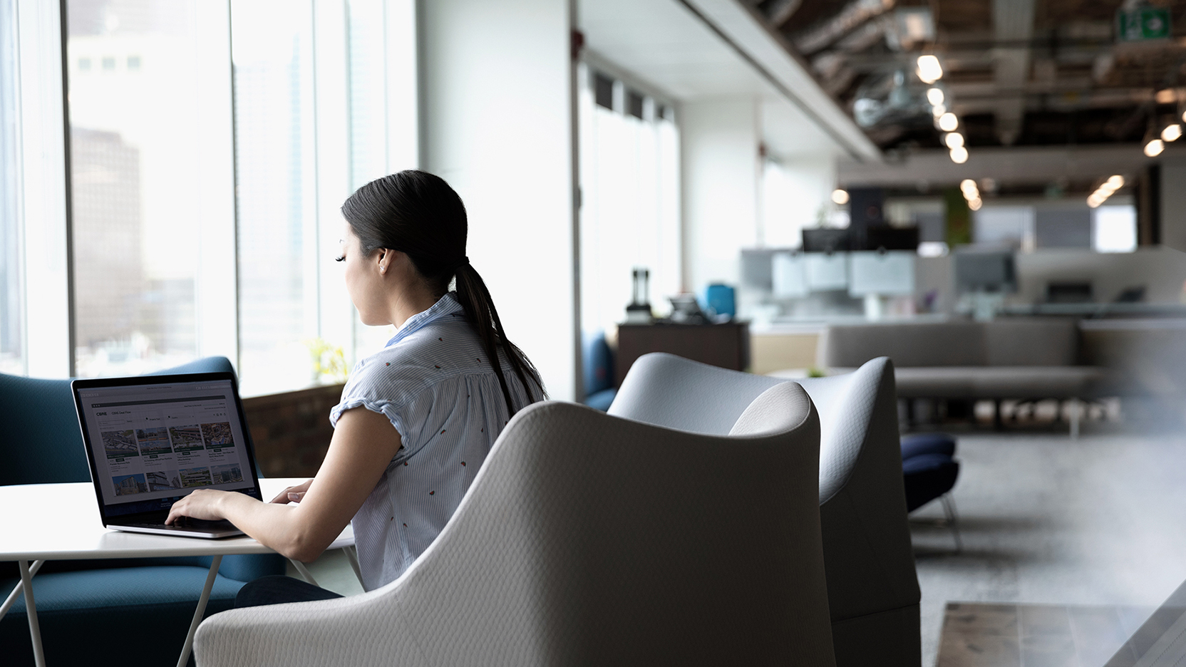 Female with laptop working at table in open office setting